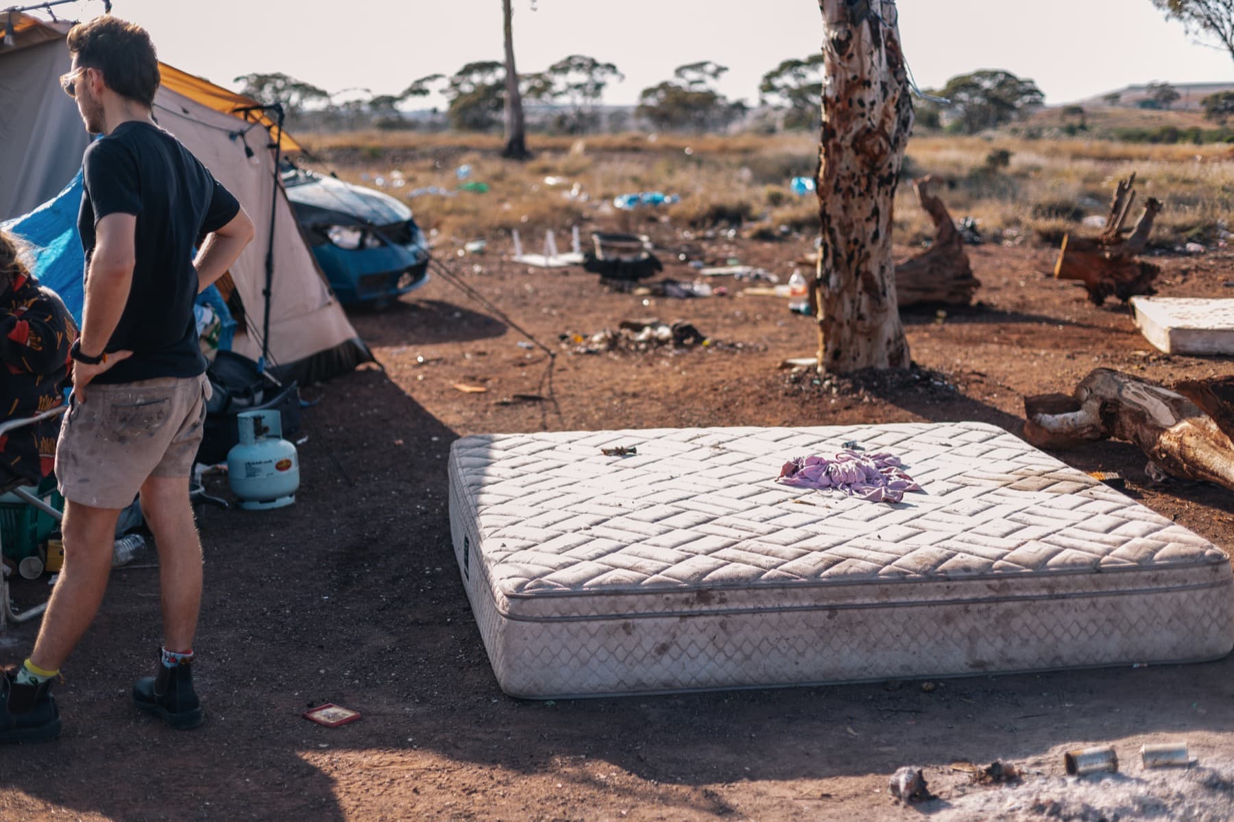 Nic standing in the camp at Ninga Mia beside a mattress on the ground