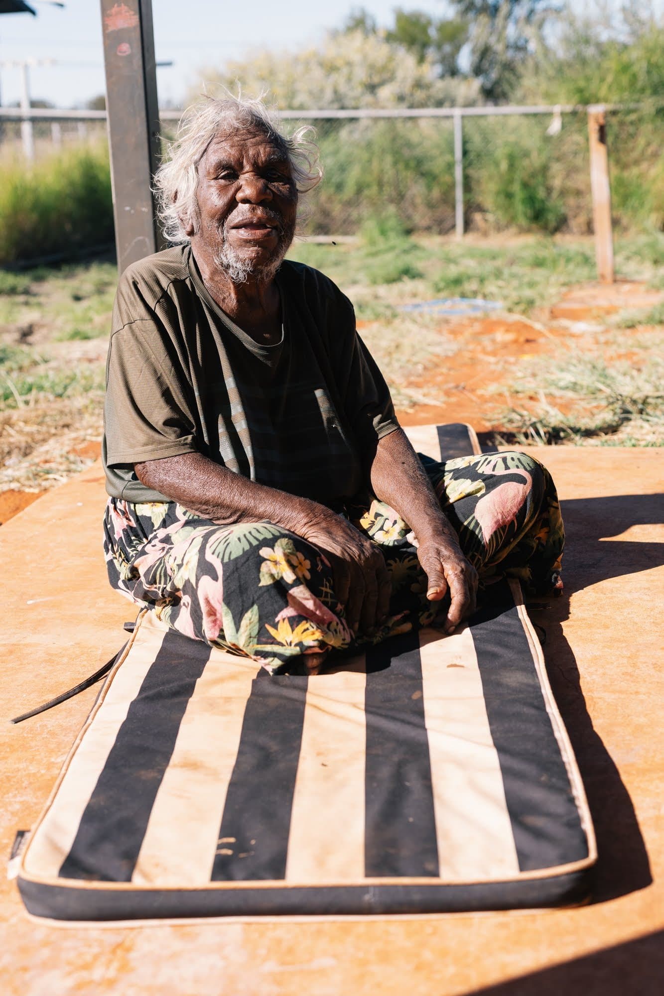 A woman sitting on a worn mat on the ground