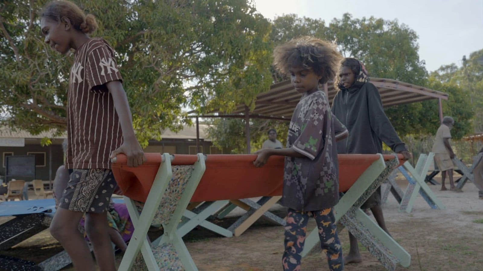 Kids carrying an orange Stretch Bed in Maningrida