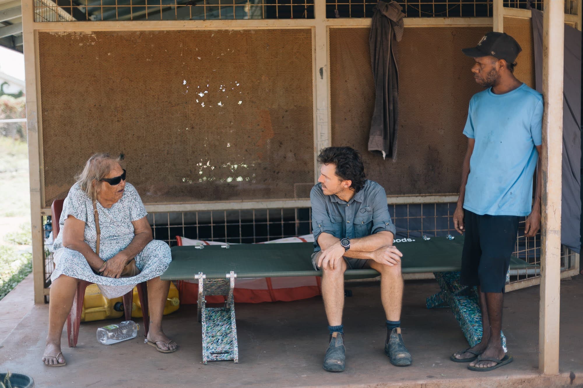 Nic sitting on a Stretch Bed with an elder on a verandah — ongoing support and connection