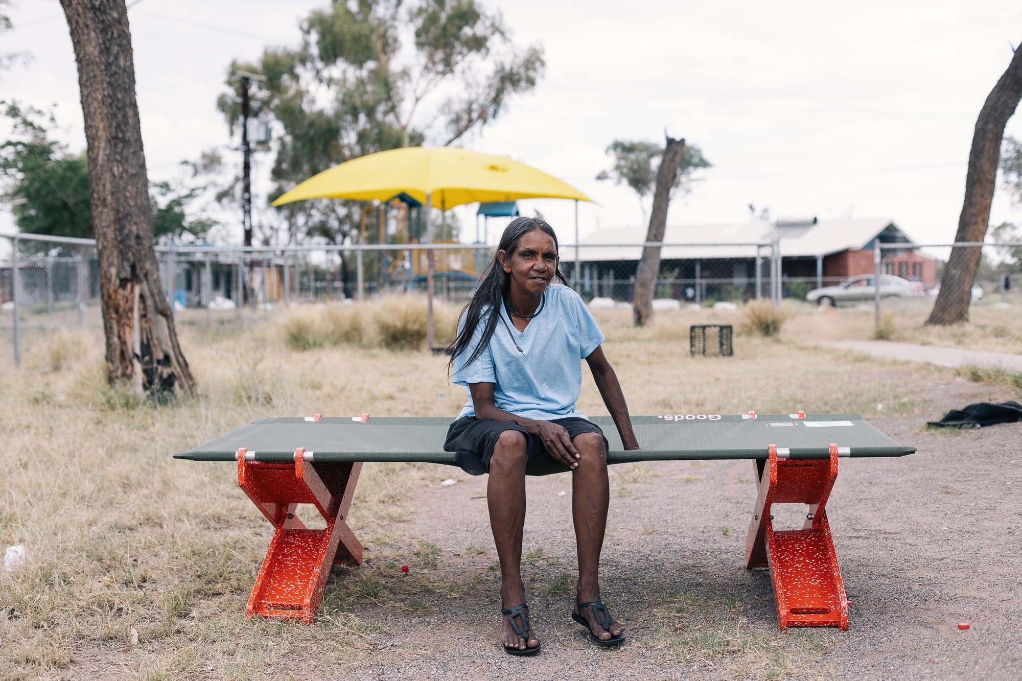 Woman sitting on Stretch Bed with red recycled plastic legs