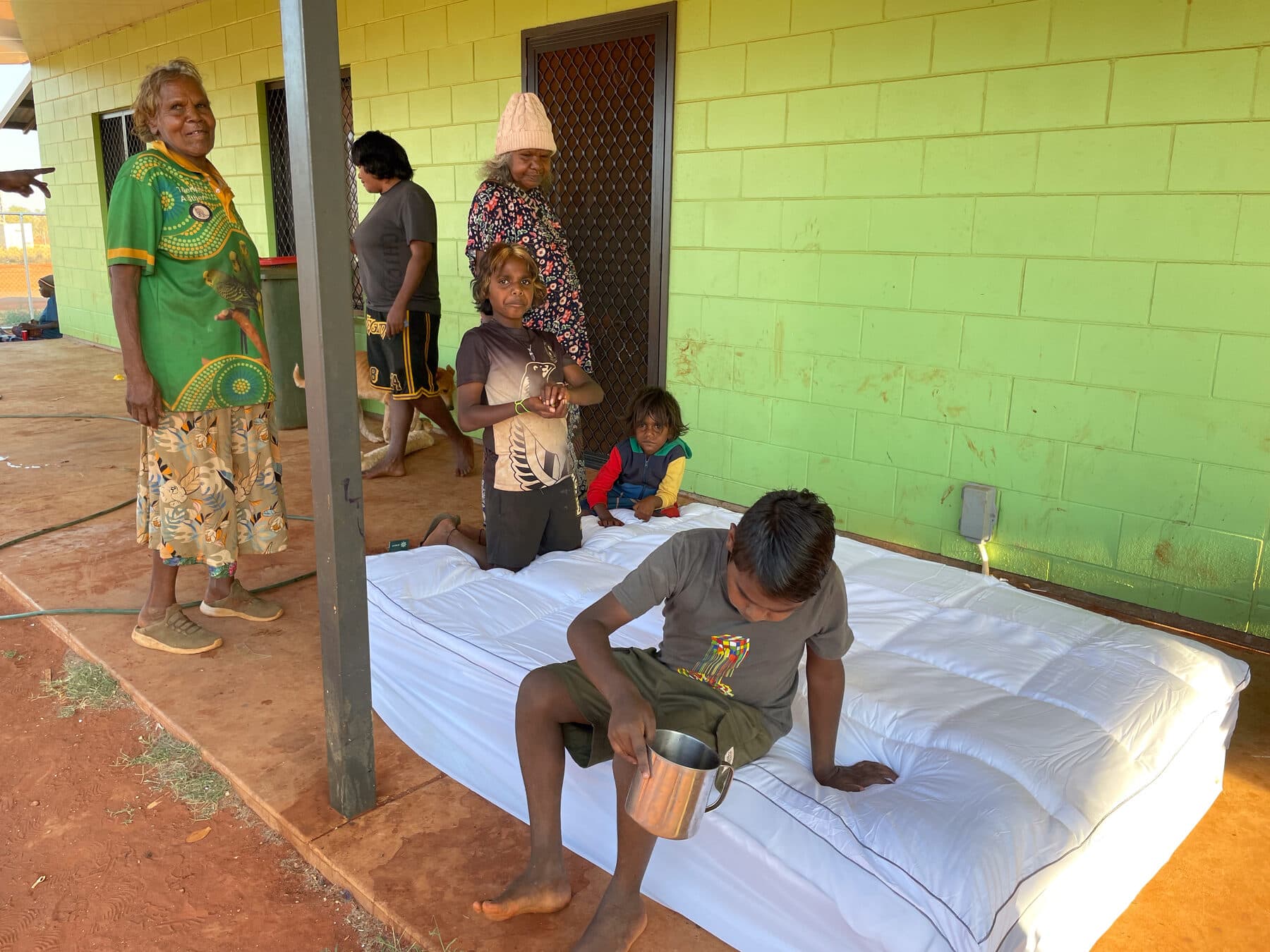A family testing a newly delivered bed on a verandah
