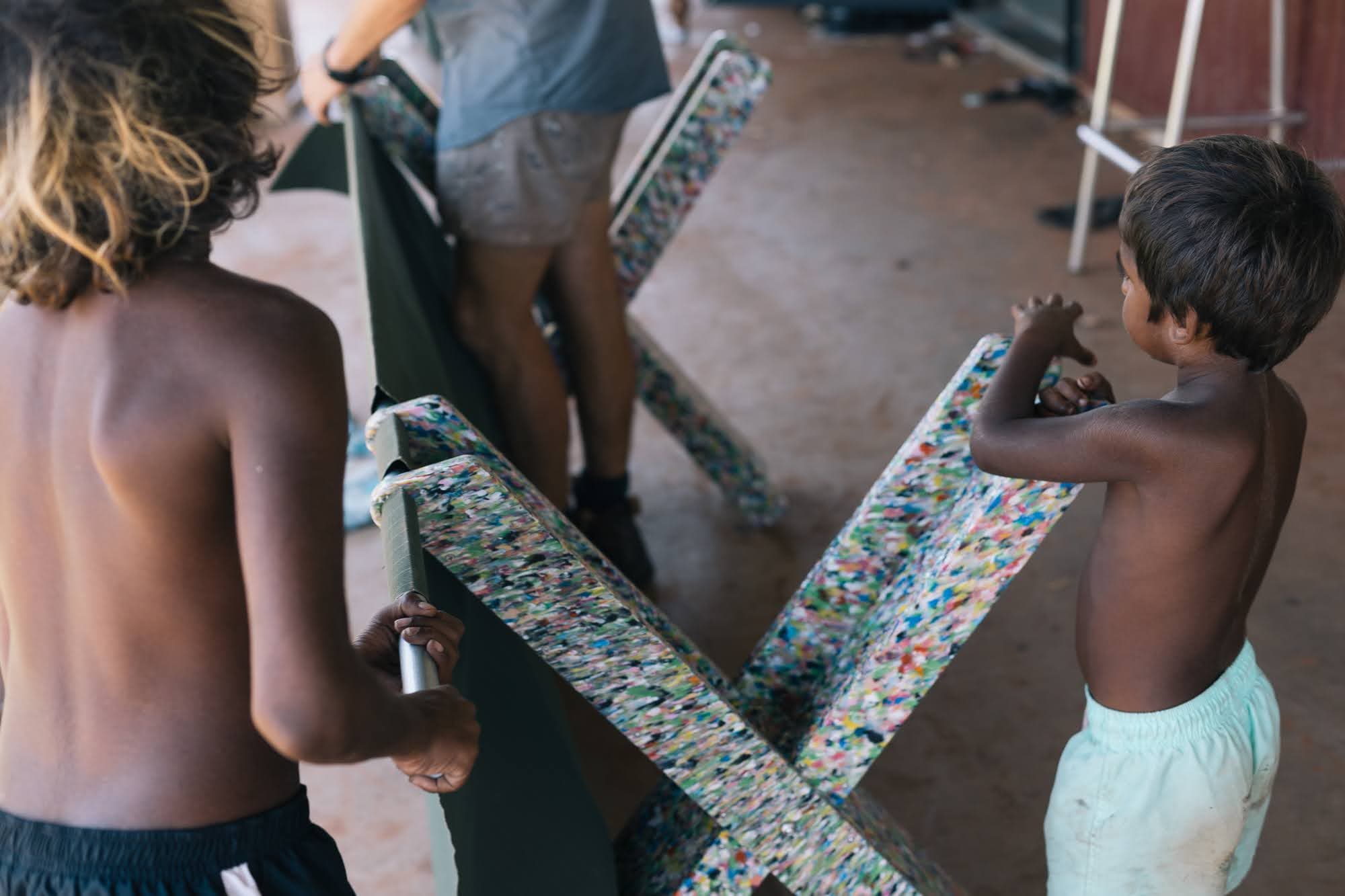 Kids in community threading steel poles through the recycled-plastic X-legs